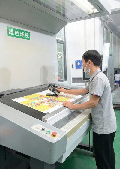 Color accuracy inspection at a printing press, technician measuring printed packaging sheets in a real China-based factory.